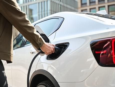 A person plugs a charging plug into an electric car to start a charging event